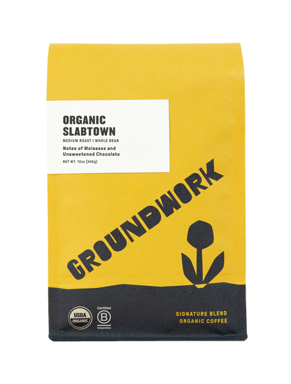 A yellow and white bag of Groundwork Coffee’s Slabtown medium roast whole bean, with a tulip design, organic labels, and notes of unsweetened chocolate.
