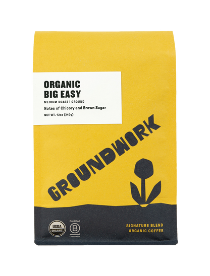 A yellow and white Groundwork Coffee Store Big Easy medium roast bag features black text, a flower graphic, and chicory notes.