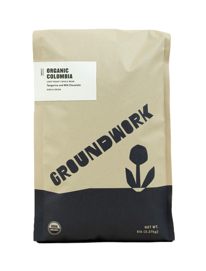 A 5-lb brown bag of Groundwork Coffees Colombia: AMUCC Fair Trade, with simple black text, a flower graphic, and notes of tangerine and milk chocolate.