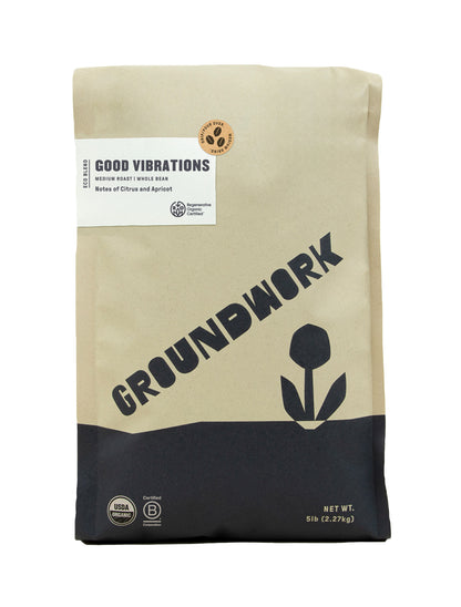 A 5lb bag of Groundwork Coffee’s Regenerative Organic Certified® Good Vibrations, medium roast whole bean with citrus notes, in tan and black packaging featuring a flower graphic.