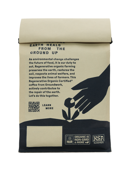 Back of Groundwork coffee bag with text promoting regenerative organic farming. Features a hand planting a flower illustration, QR code with ‘Learn more’, and certifications including Organic, Non-GMO, and Kosher.
