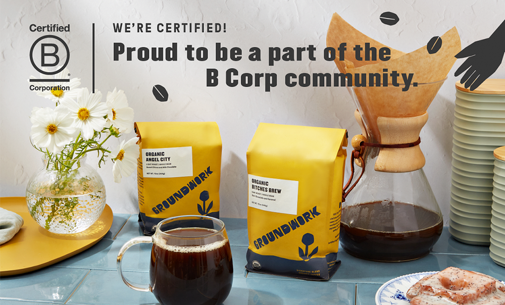 Coffee bags and a Chemex coffee maker on a counter with flowers and a mug. Text reads, “Proud to be a part of the B Corp community. We’re certified!” B Corp logo is shown.