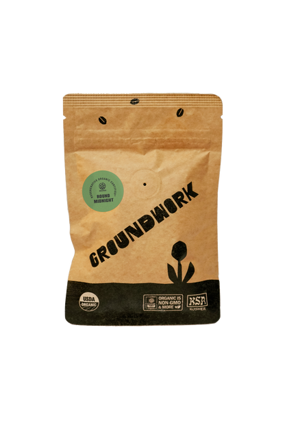 A kraft paper 2oz sample coffee pouch labeled “GROUNDWORK” with a black base and flower logo, featuring a green circular sticker that reads “Regenerative Organic Certified – Round Midnight.” 
The pouch also displays USDA Organic, KSA Kosher, and “Organic is Non-GMO & More” certification logos at the bottom.