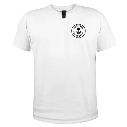 Photo of a white T-shirt with a small circular Groundwork logo on the left chest that reads EST. 1990 LOS ANGELES around a black flower icon.