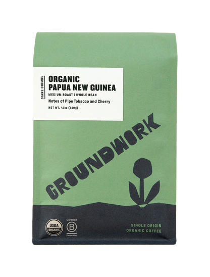 A green bag of Groundwork Coffee Store’s Papua New Guinea: Siane Chimbu whole bean coffee with pipe tobacco and cherry notes, featuring a flower graphic and certification logos.
