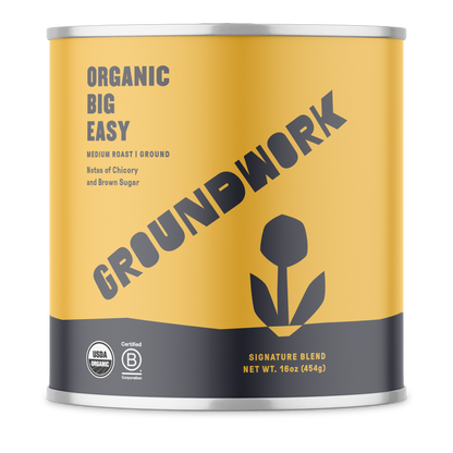 A yellow can of Groundwork Coffee Stores Big Easy ground coffee with chicory, flower graphic, and certification logos on the front.