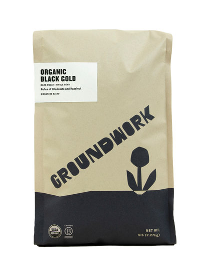 A 5 lb (2.27 kg) beige and black bag of Groundwork Coffee's Black Gold dark roast whole bean coffee with hazelnut notes.
