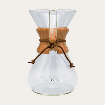 The Chemex Brewer from Groundwork Coffee features a glass body, wooden collar, and leather tie, using conical filters, shown on a plain light background.